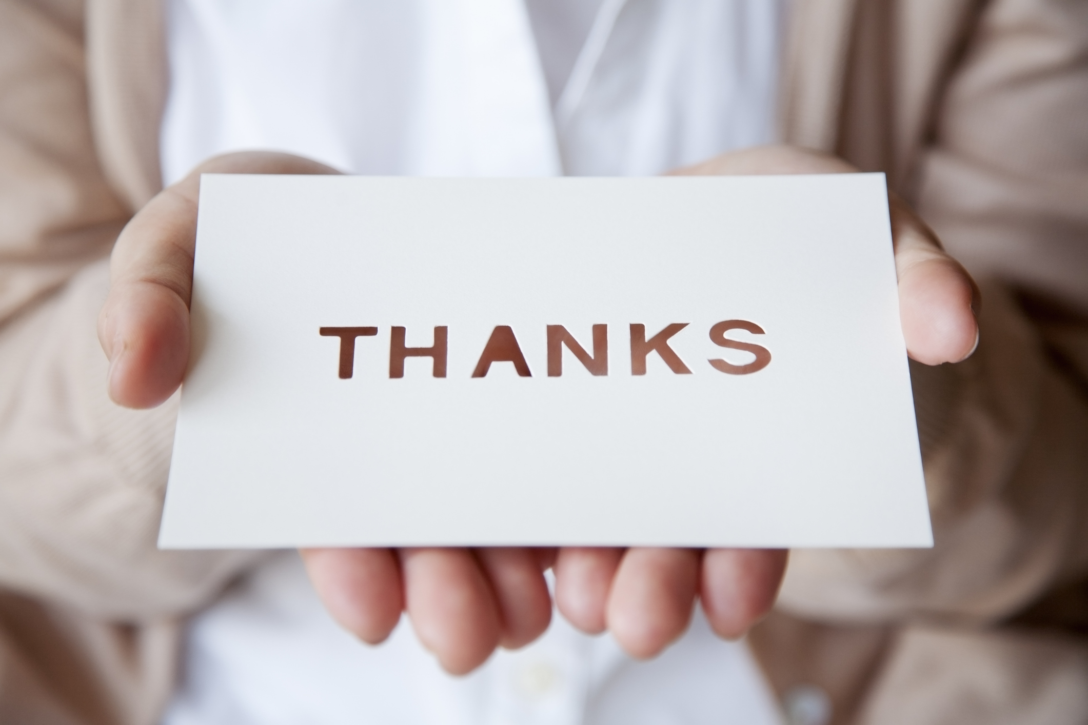 Person holding a card with &quot;THANKS&quot; written on it