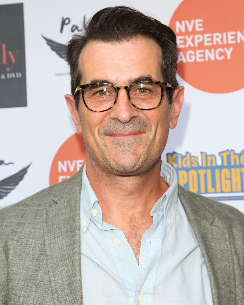 Ty Burrell in glasses smiling at event, wearing a casual shirt and jacket