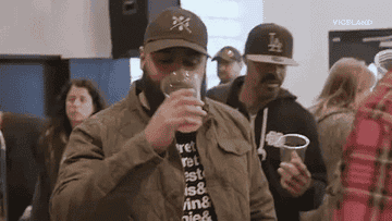 Two individuals sampling beer at a tasting event, one holding a glass up close