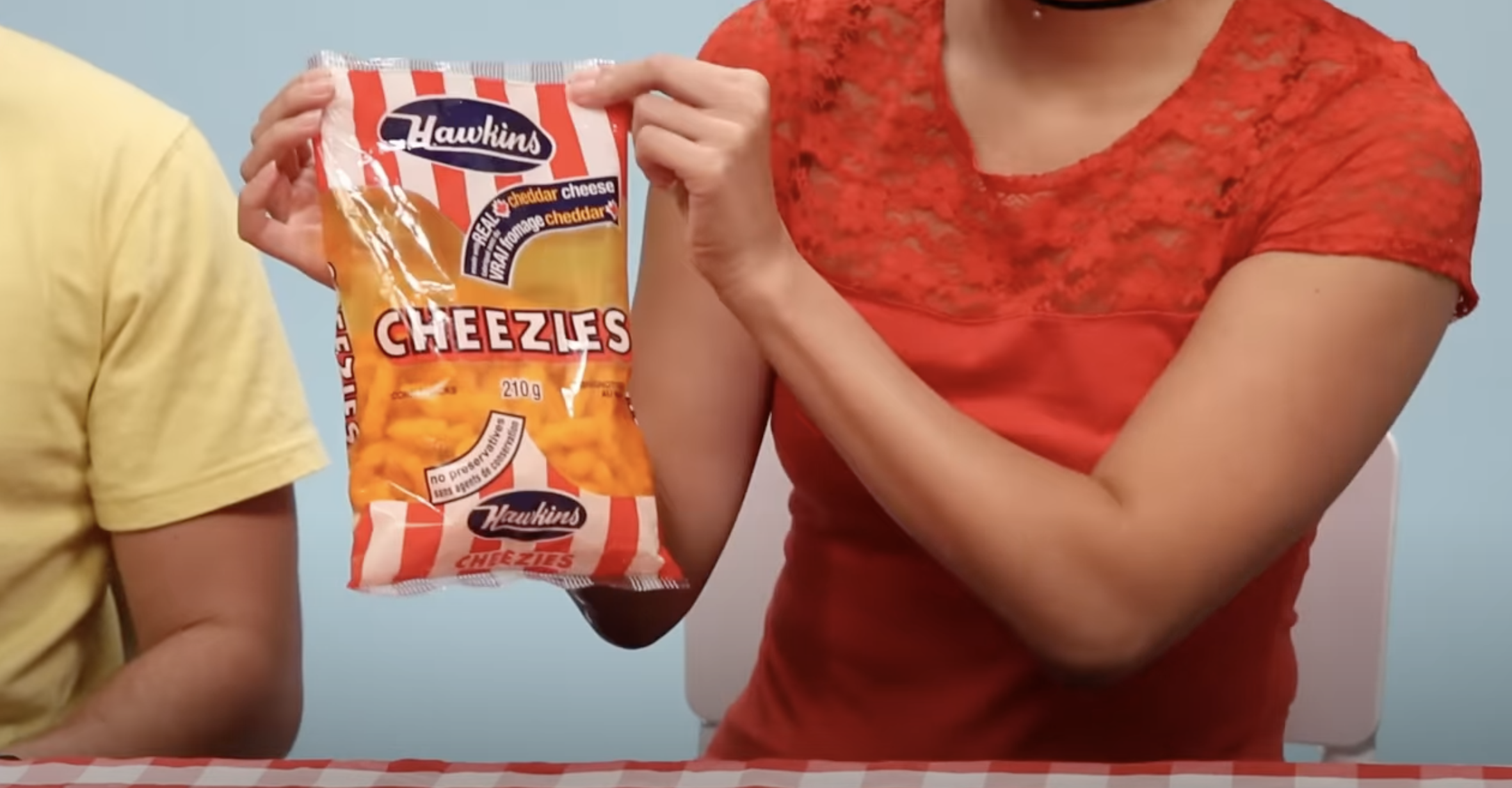 Person holding a bag of Hawkins Cheezies; another individual partially visible