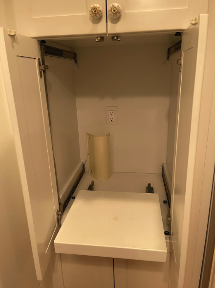 An open, empty built-in ironing board cabinet