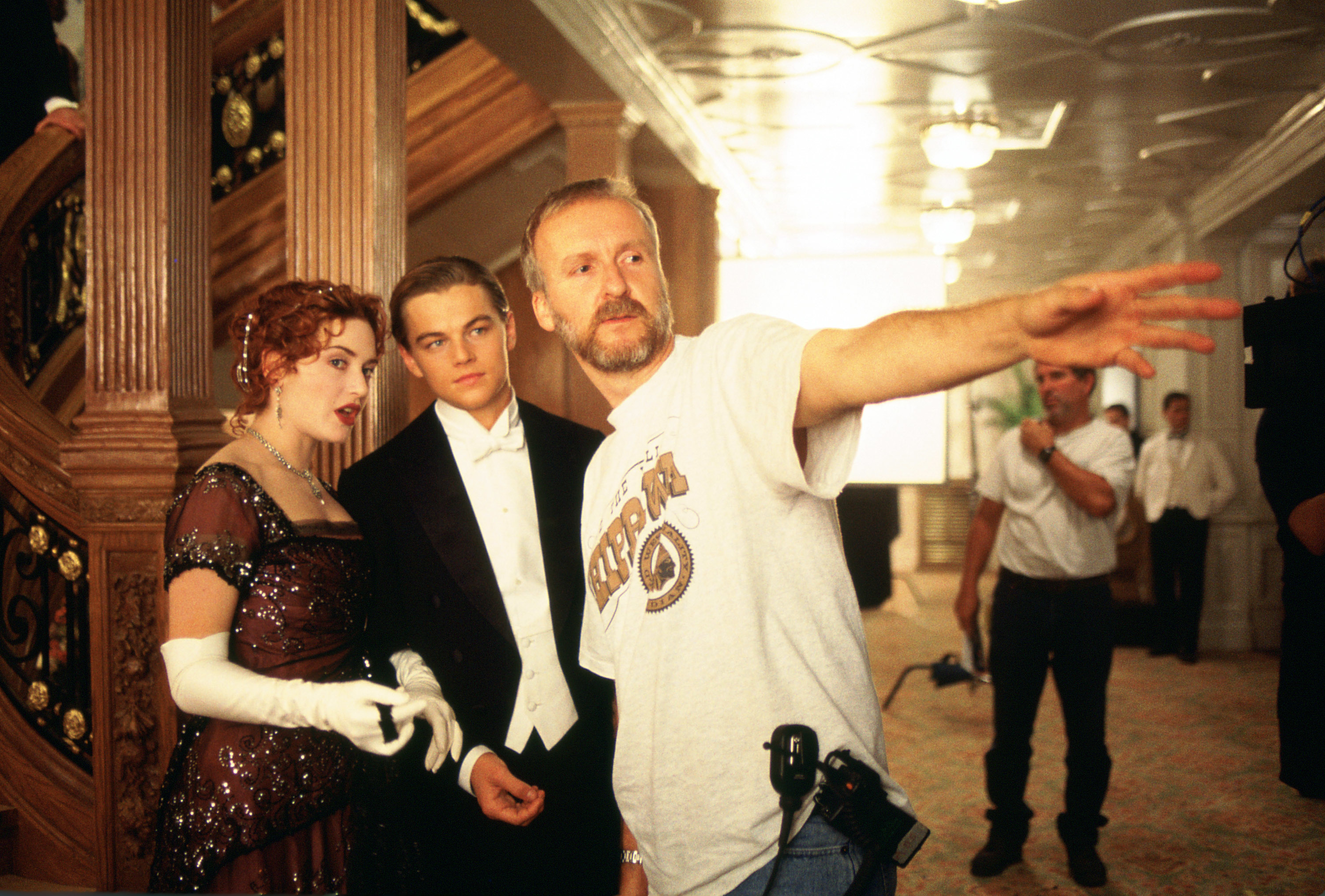 Director with actors on movie set, man points off-camera, both in vintage attire