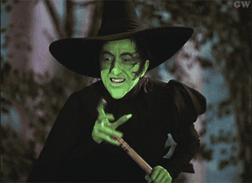 Character from &#x27;The Wizard of Oz&#x27; dressed as a witch, pointing and smiling