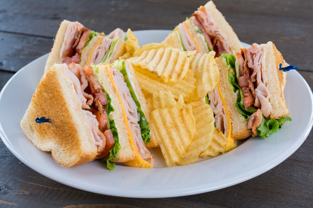 A plate with cut club sandwiches and potato chips