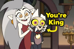 Eda holding up King with both of her hands on the side of his mouth. King looks concerned.