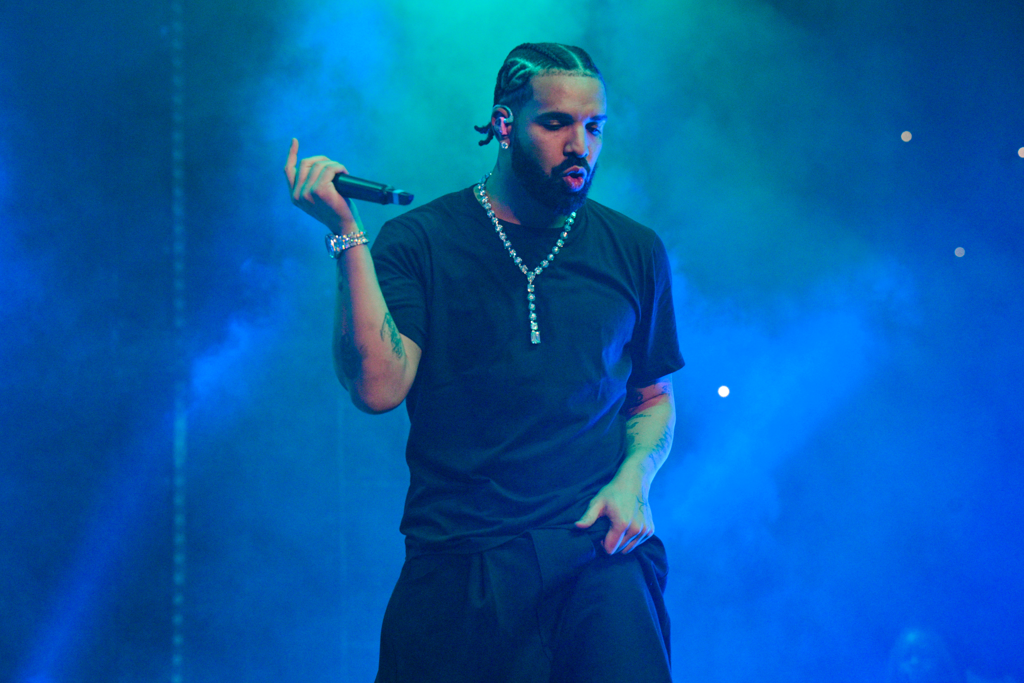Drake on stage holding a microphone during a performance