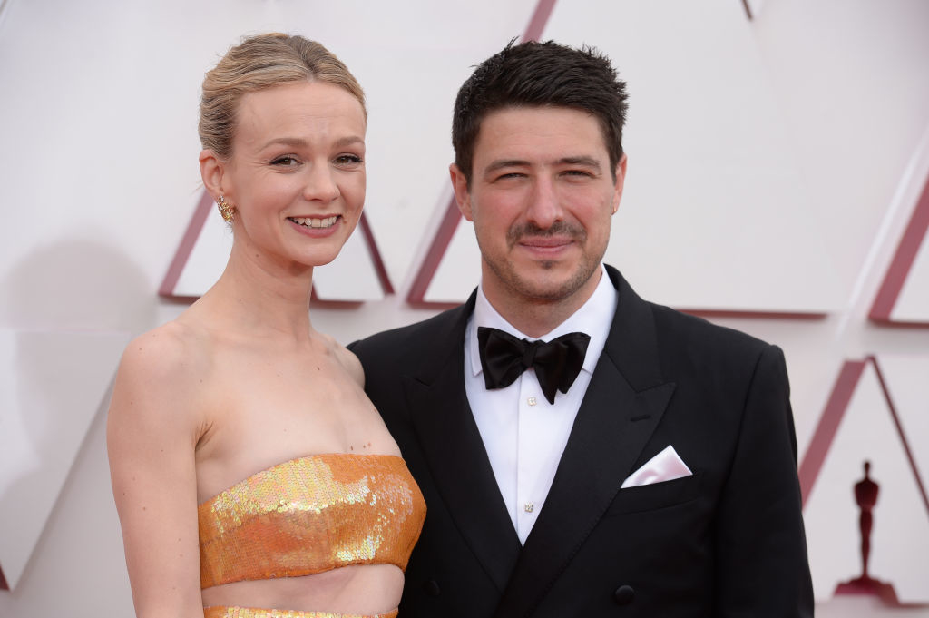 Carey Mulligan and Marcus Mumford smiling at a formal event, one in a strapless metallic gown and the other in a black tuxedo with bow tie