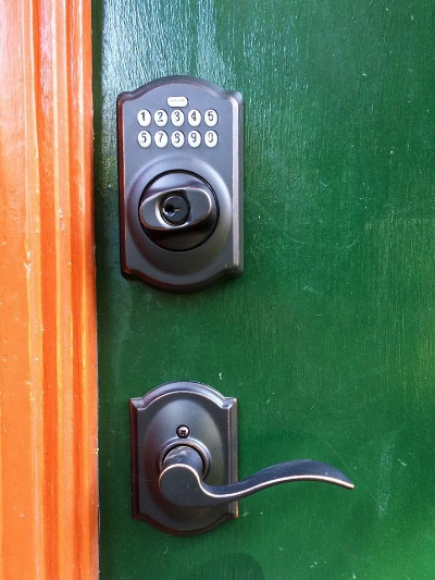 A black digital keypad lock above a matching handle on a green door