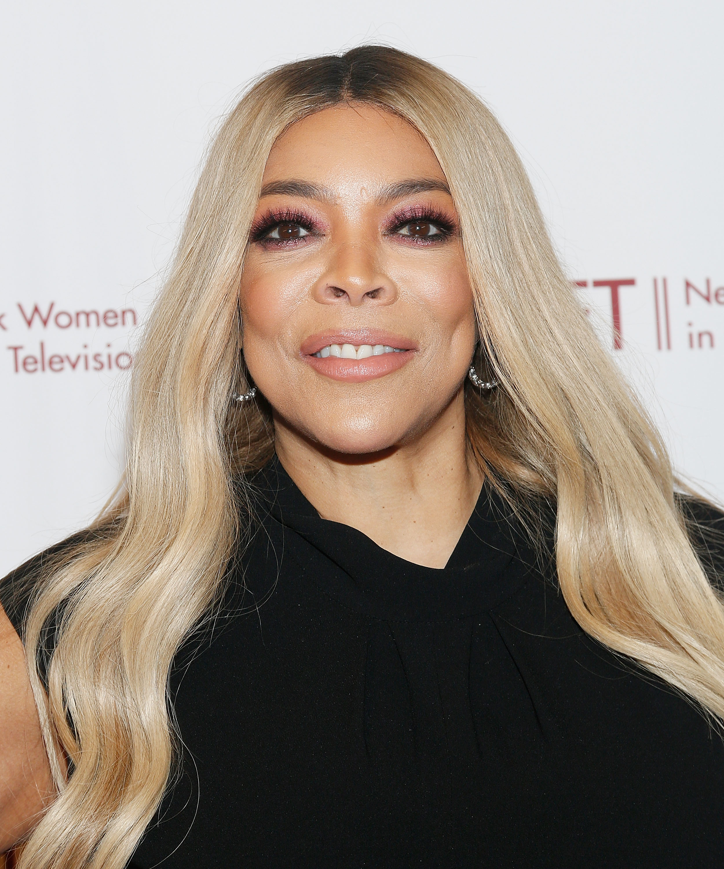 A closeup of Wendy Williams wearing a dress, smiling at an event