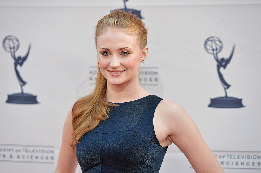 Sophie Turner posing in a sleeveless dress at an event