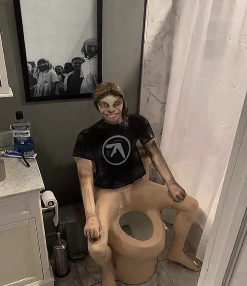 Lifesize figure with a smiley face head and human body sitting on a toilet