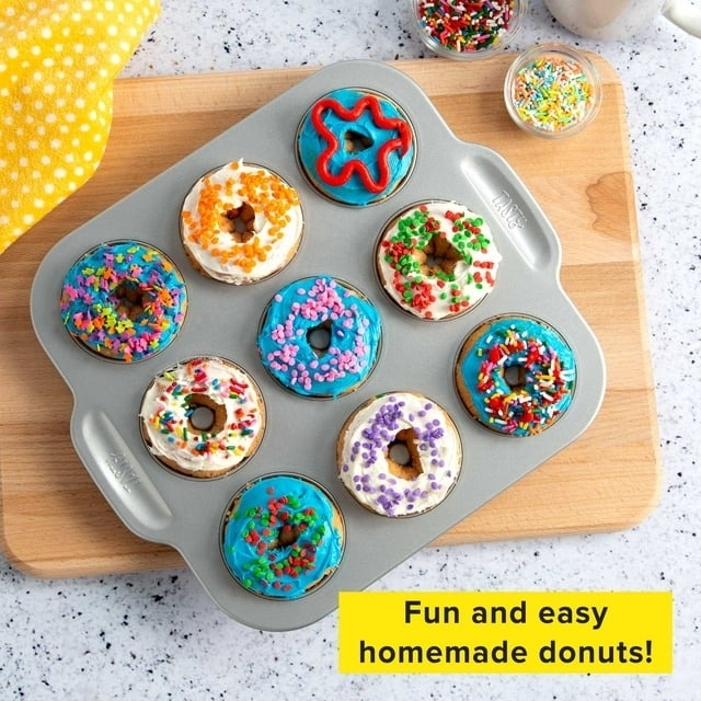 Assorted homemade donuts with various toppings on a baking tray, text reads &#x27;Fun and easy homemade donuts!&#x27;