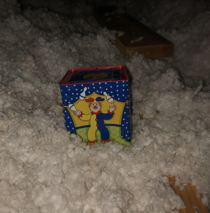 A Jack-in-the-box toy partially buried in white insulation materials