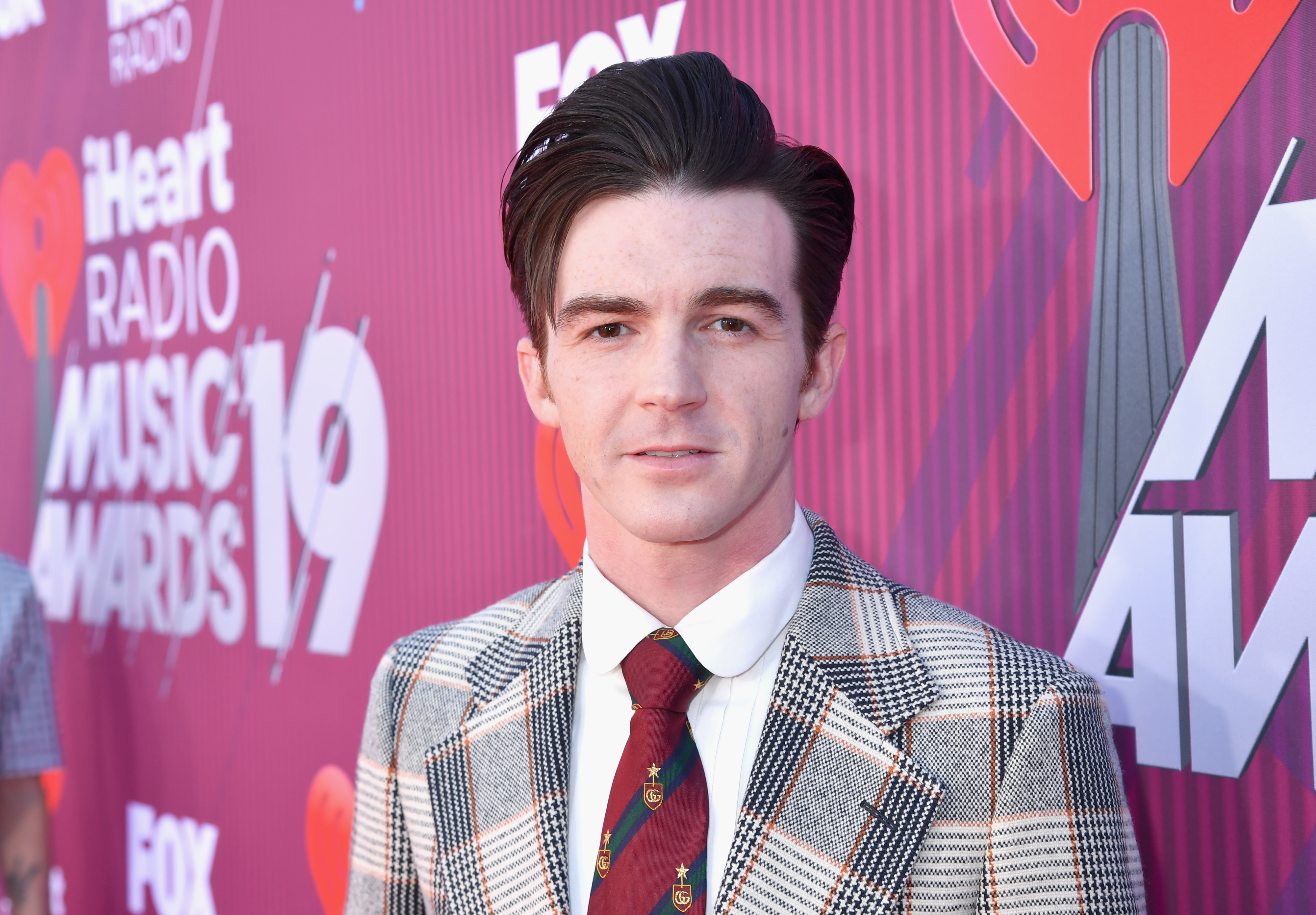 Drake Bell in a patterned suit poses at iHeartRadio Music Awards