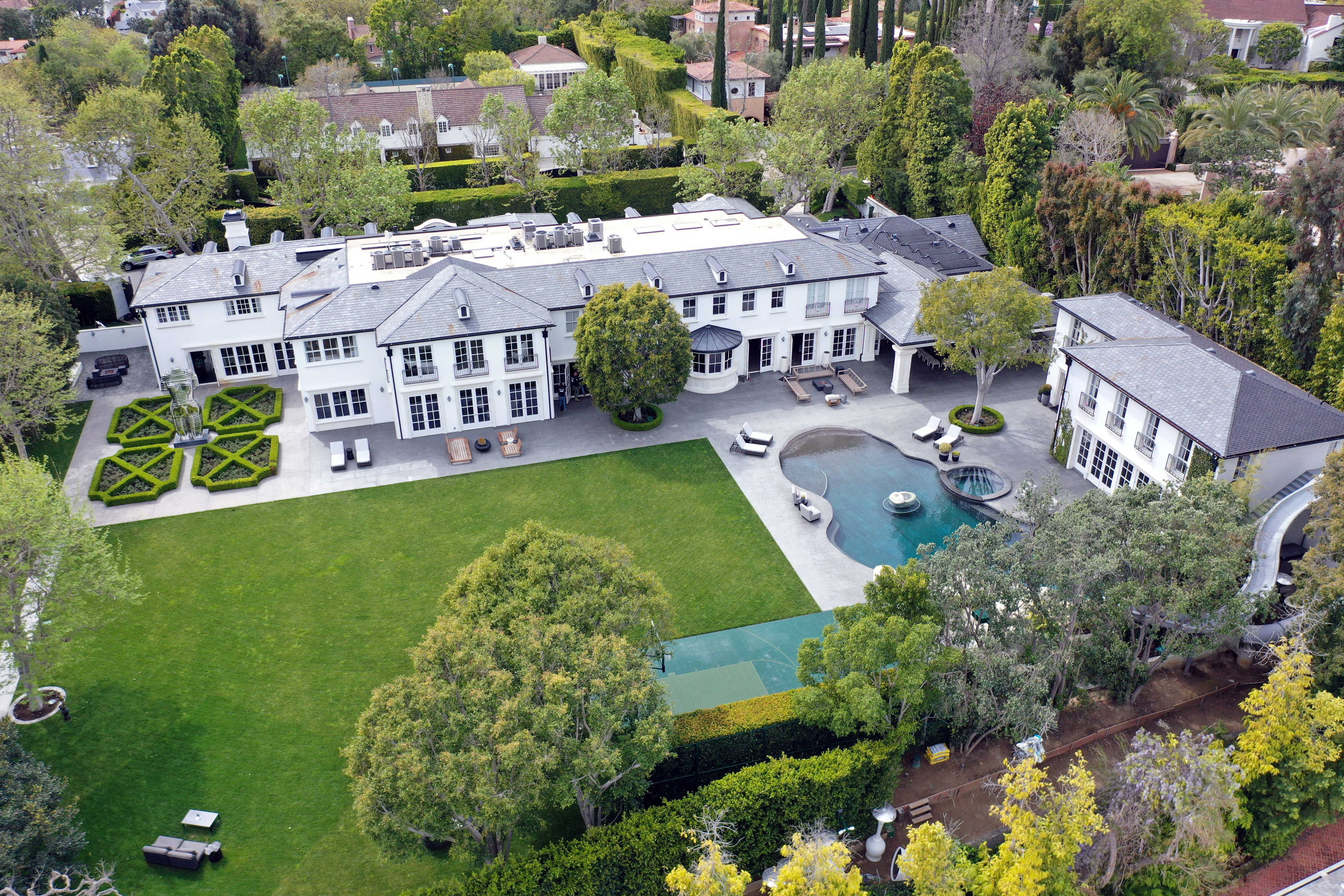 Aerial view of a large, luxurious estate with multiple buildings, landscaped gardens, and a swimming pool