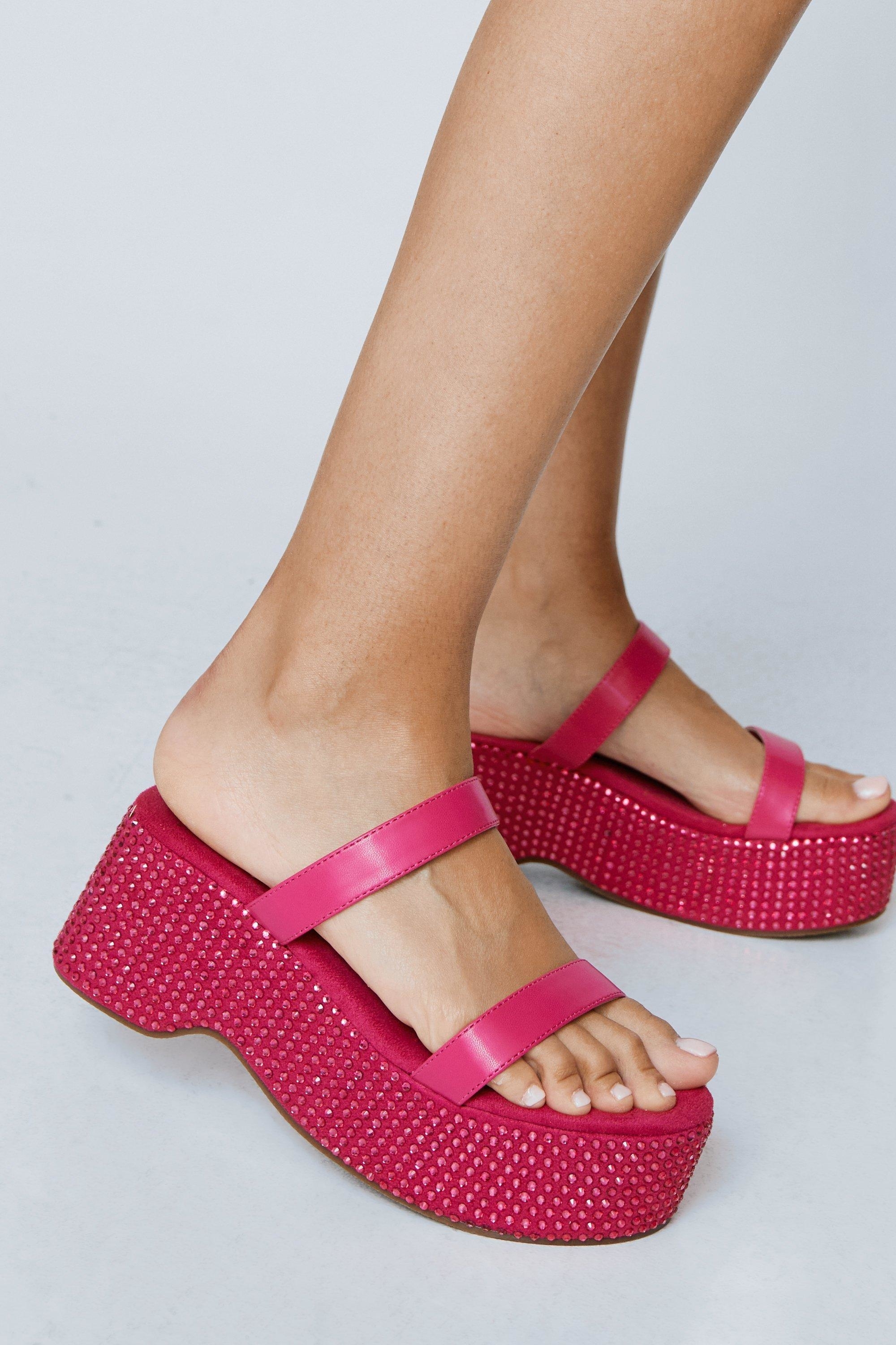 Close-up of a person wearing pink platform sandals with embellished details