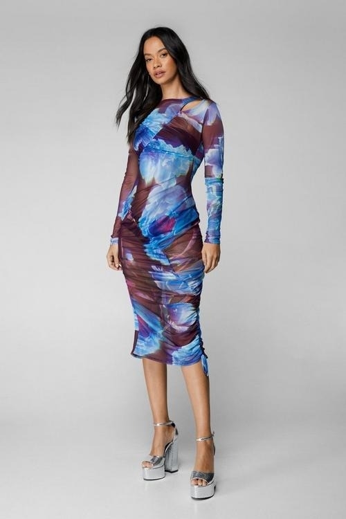 model in a fitted, printed midi dress with a high neckline and long sleeves, paired with platform heels