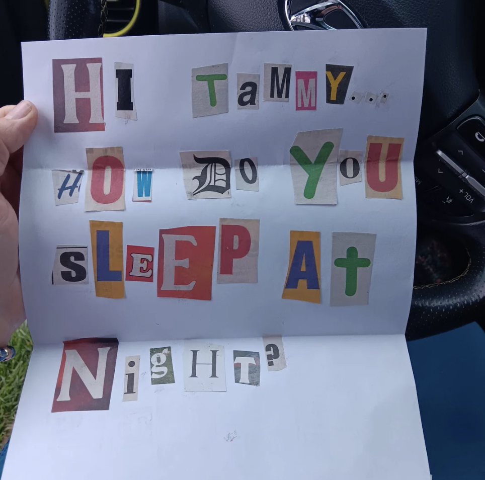 Paper with cutout letters forming the message &quot;HI TaMMy HOW DO YOU SLEeP AT NIGHT?&quot; held in a car
