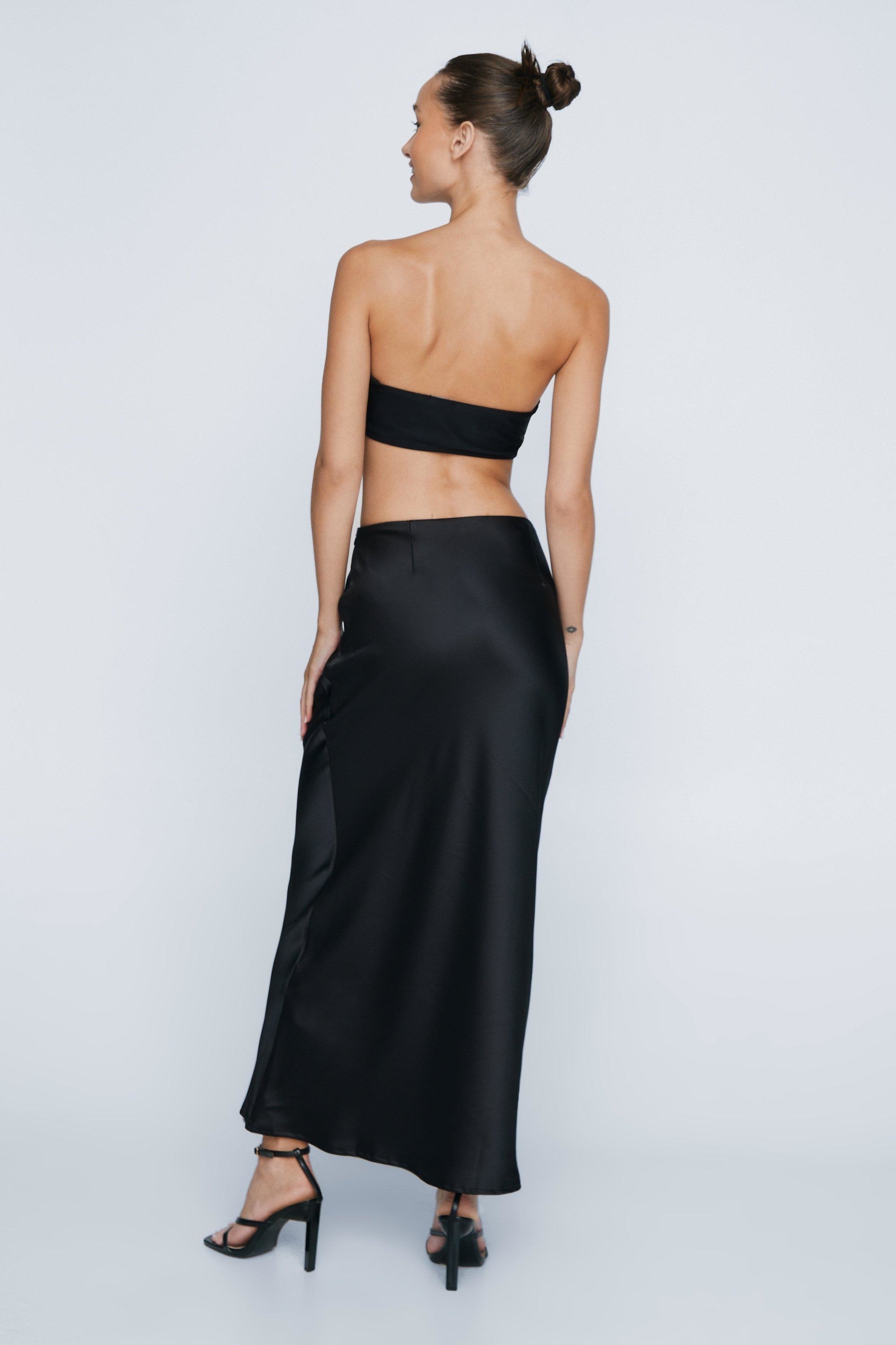 model in a two-piece black ensemble with a crop top and long skirt, viewed from behind