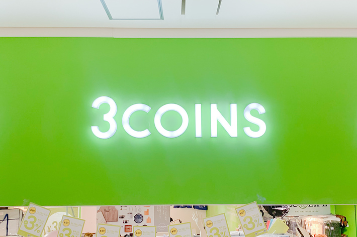 店舗の看板に「3COINS」と表示しているシーンです。