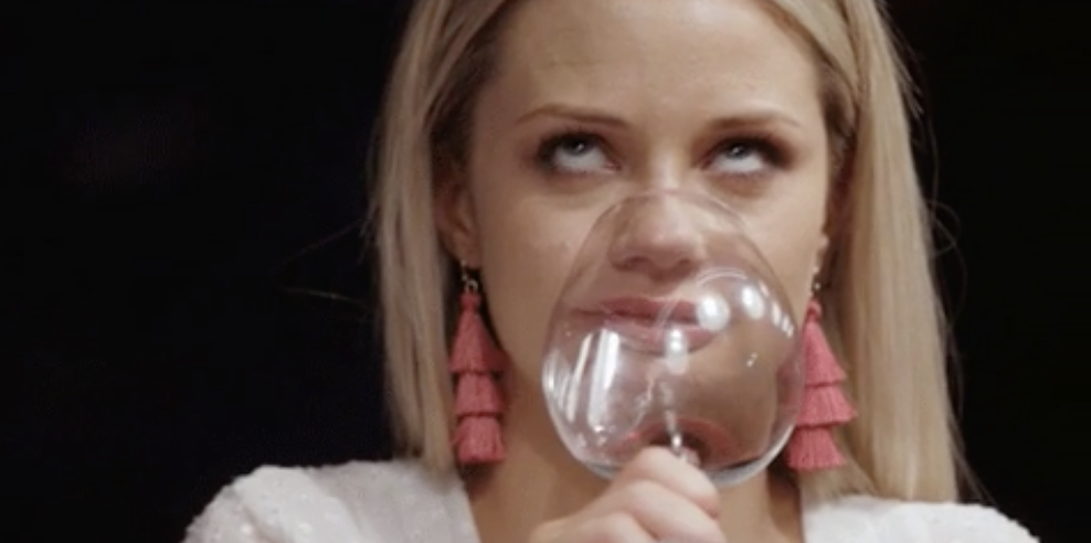 Person holding a wine glass up to their face, distorting their features for a humorous effect