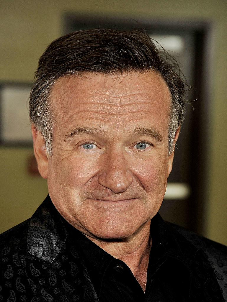 Robin Williams smiling in a black patterned shirt