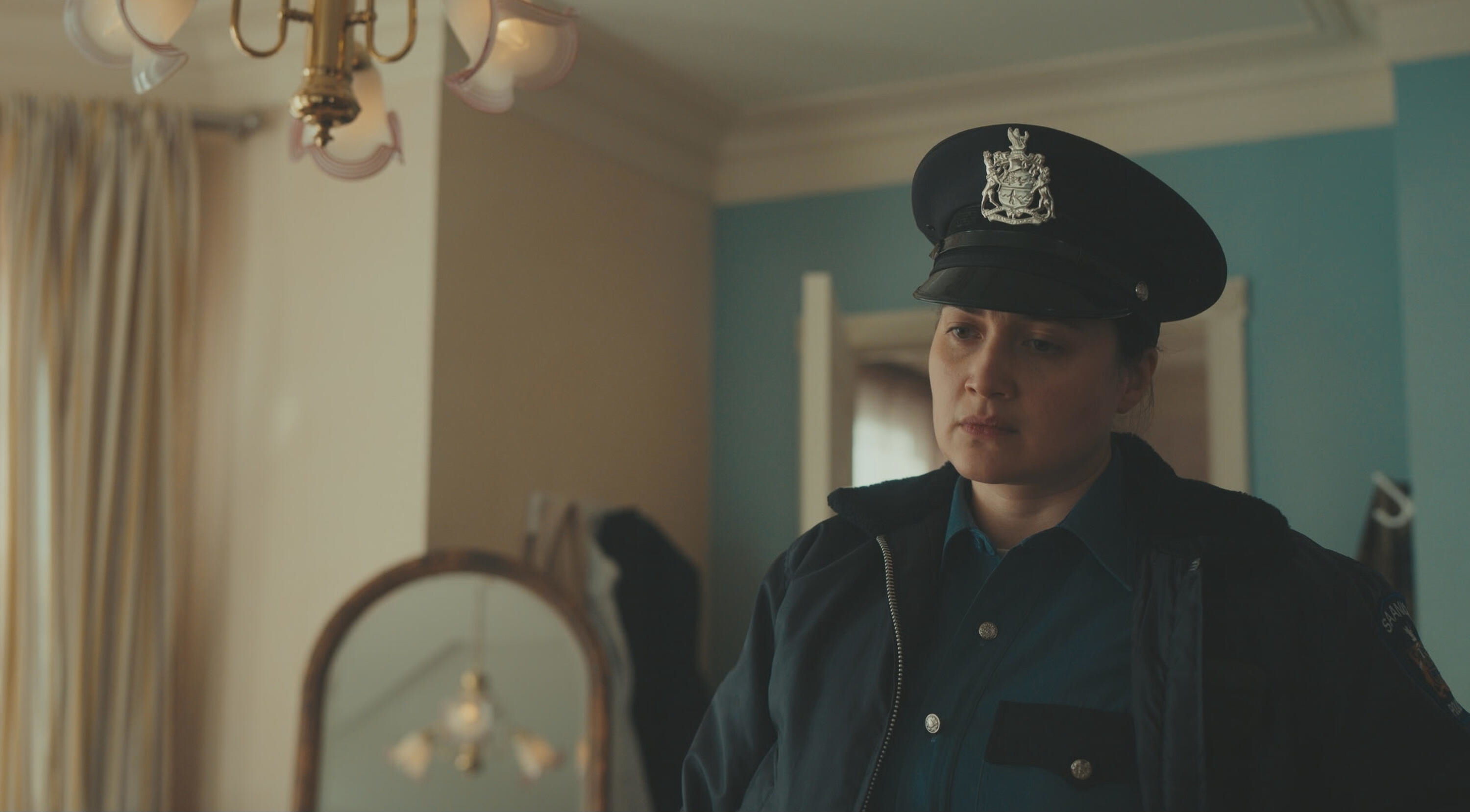 A uniformed police officer character appears concerned in a room; scene from a TV show