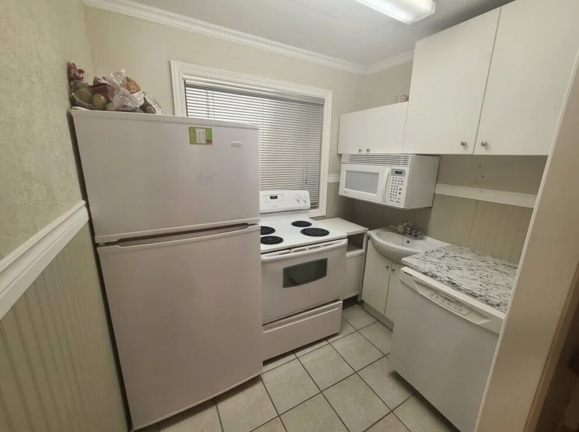 A small kitchen with a fridge, stove, microwave, and washing machine