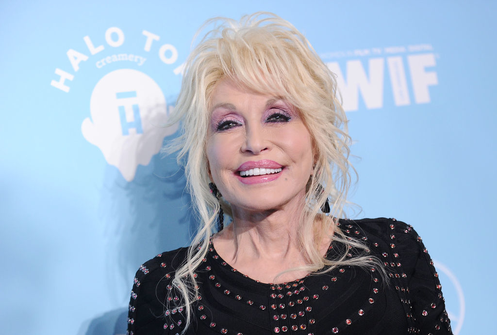 Dolly Parton smiling at an event, wearing a black top with silver embellishments