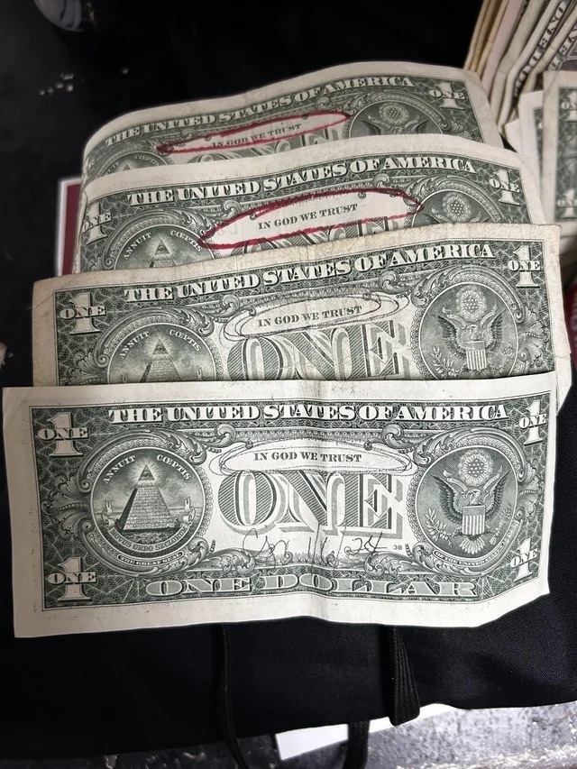 A stack of US one-dollar bills with &quot;In God We Trust&quot; circled
