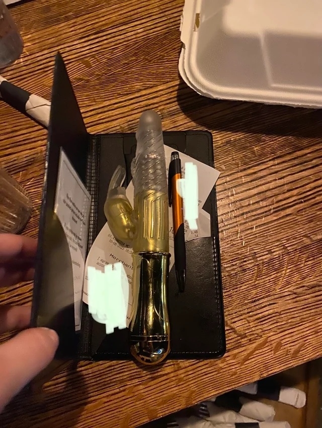 A waiter&#x27;s organizer with receipts, a pen, and a sex toy