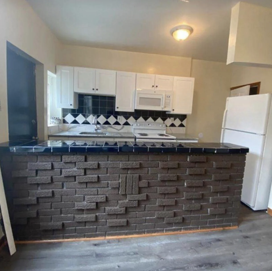 Kitchen interior with white cabinets, a fridge, and a patterned backsplash