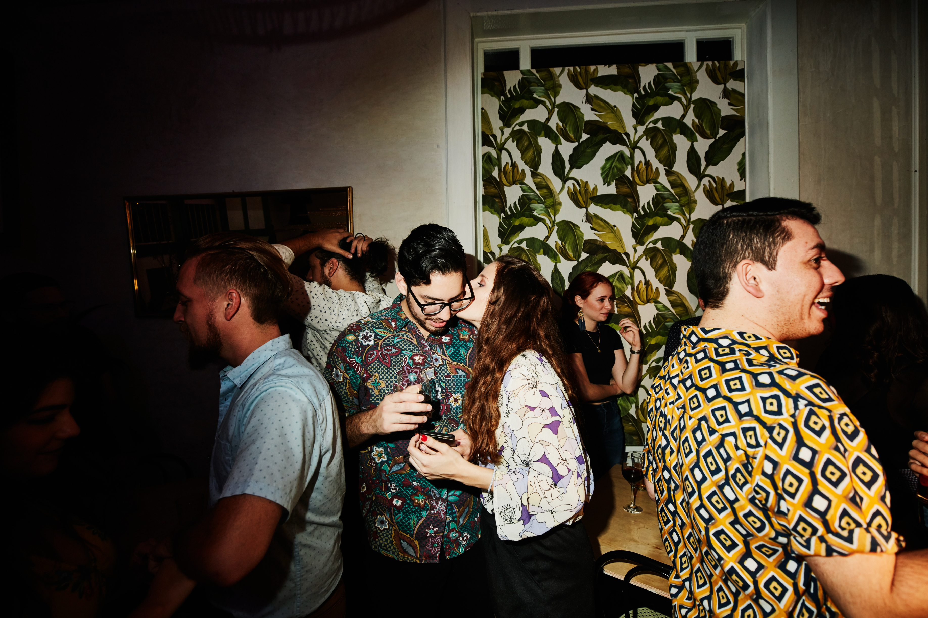 People socializing at an indoor gathering, with one person checking a phone