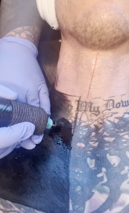 Close-up of a tattoo being inked on skin with existing tattoos, artist's gloved hands shown