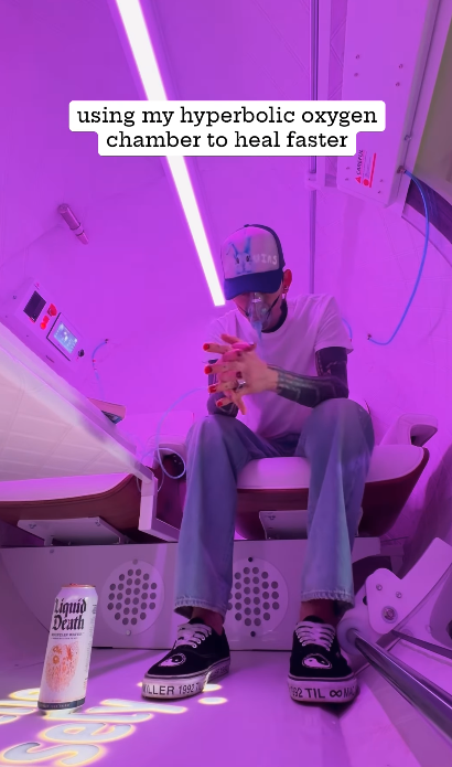 Person in a hyperbolic oxygen chamber holding a beverage