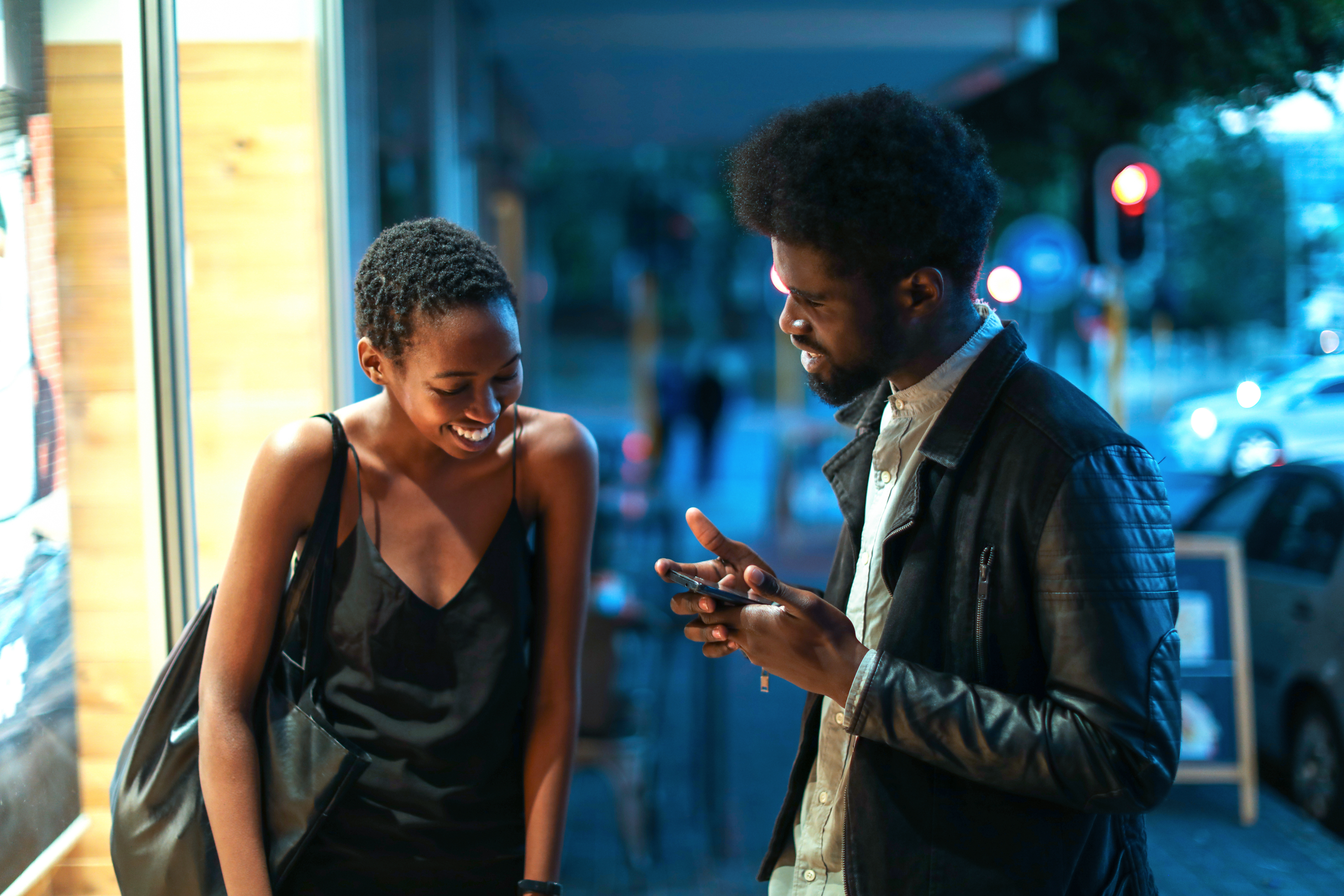 Two people sharing a joyful moment looking at a smartphone at night