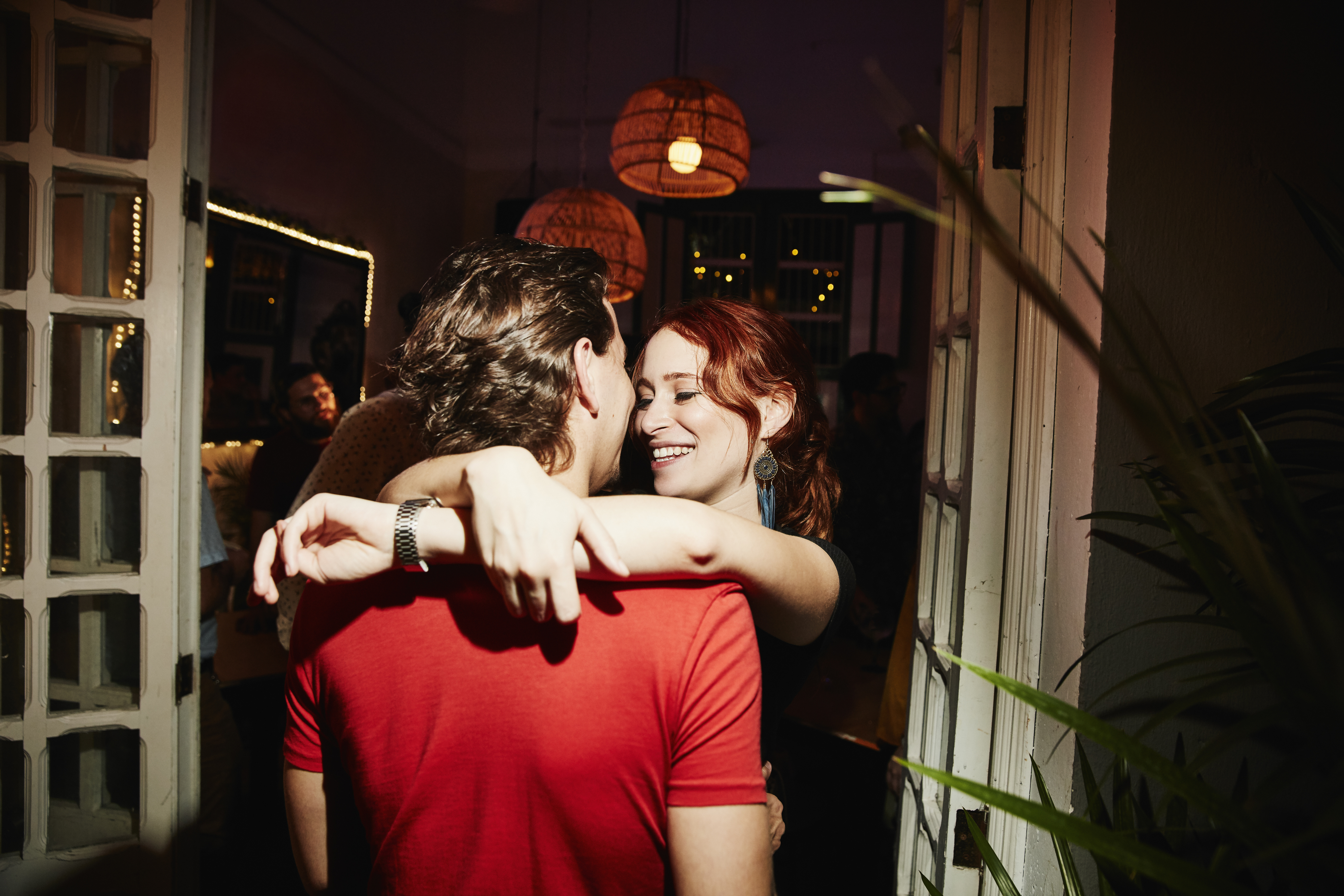 Two individuals embracing in an indoor setting, sharing a joyful moment