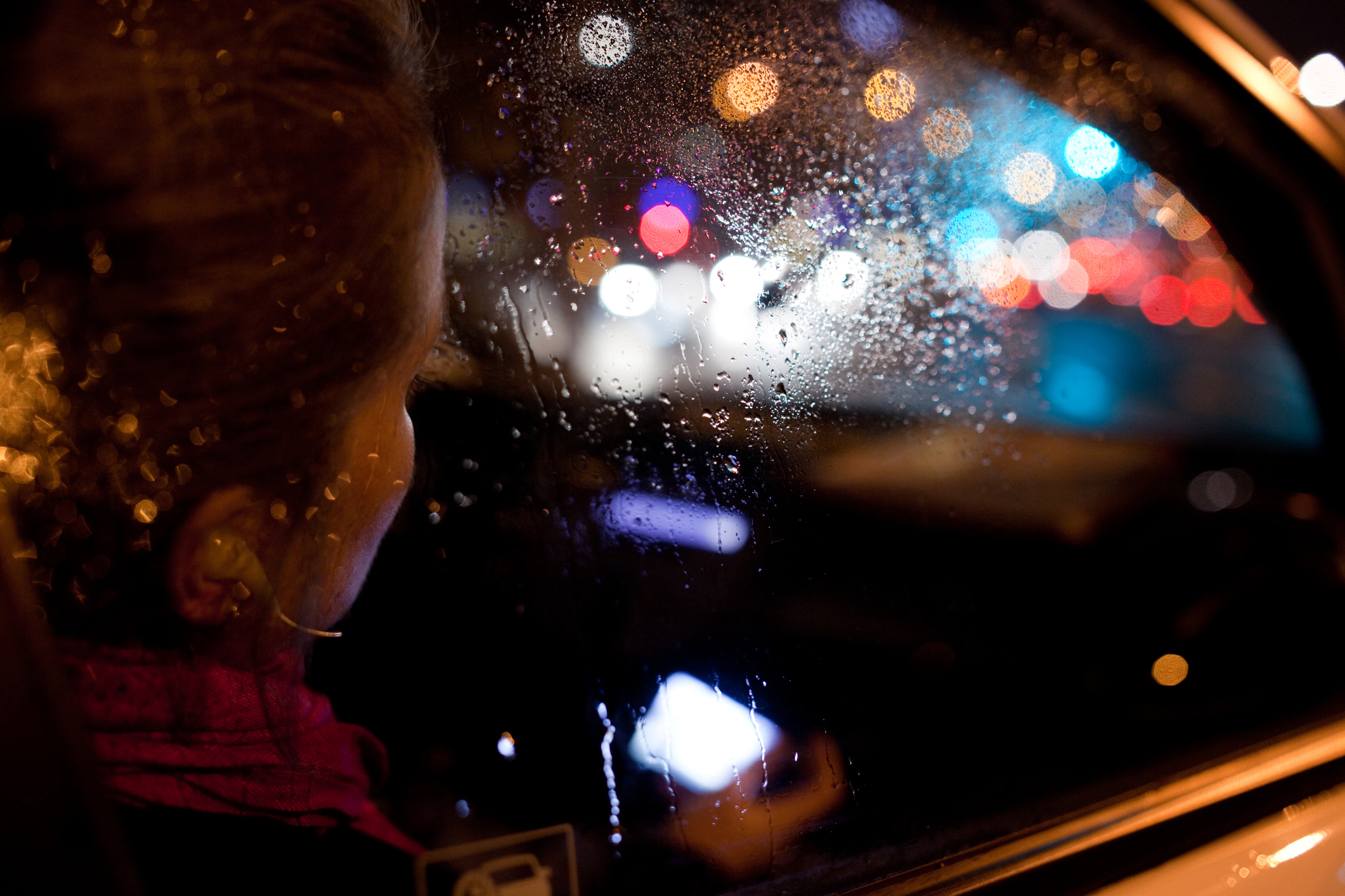 Child looking out car window at night with blurred city lights in the background