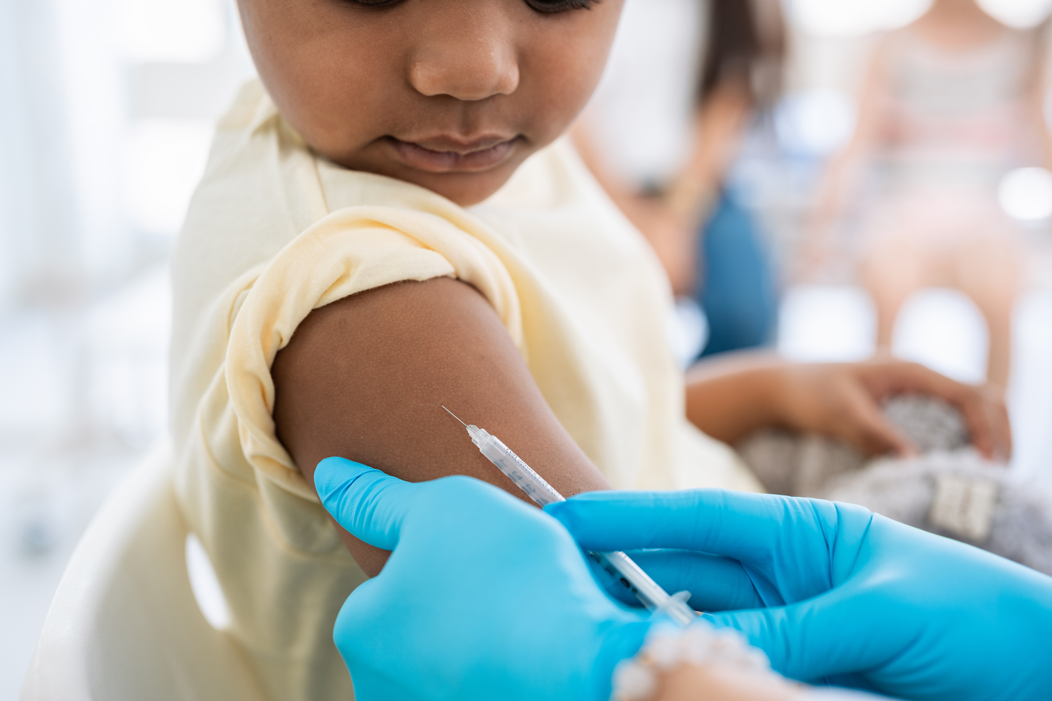 Child receiving a vaccination with a parent in the background