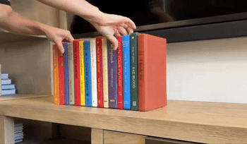 person picking up faux book display to show the back and how it conceals eyesores
