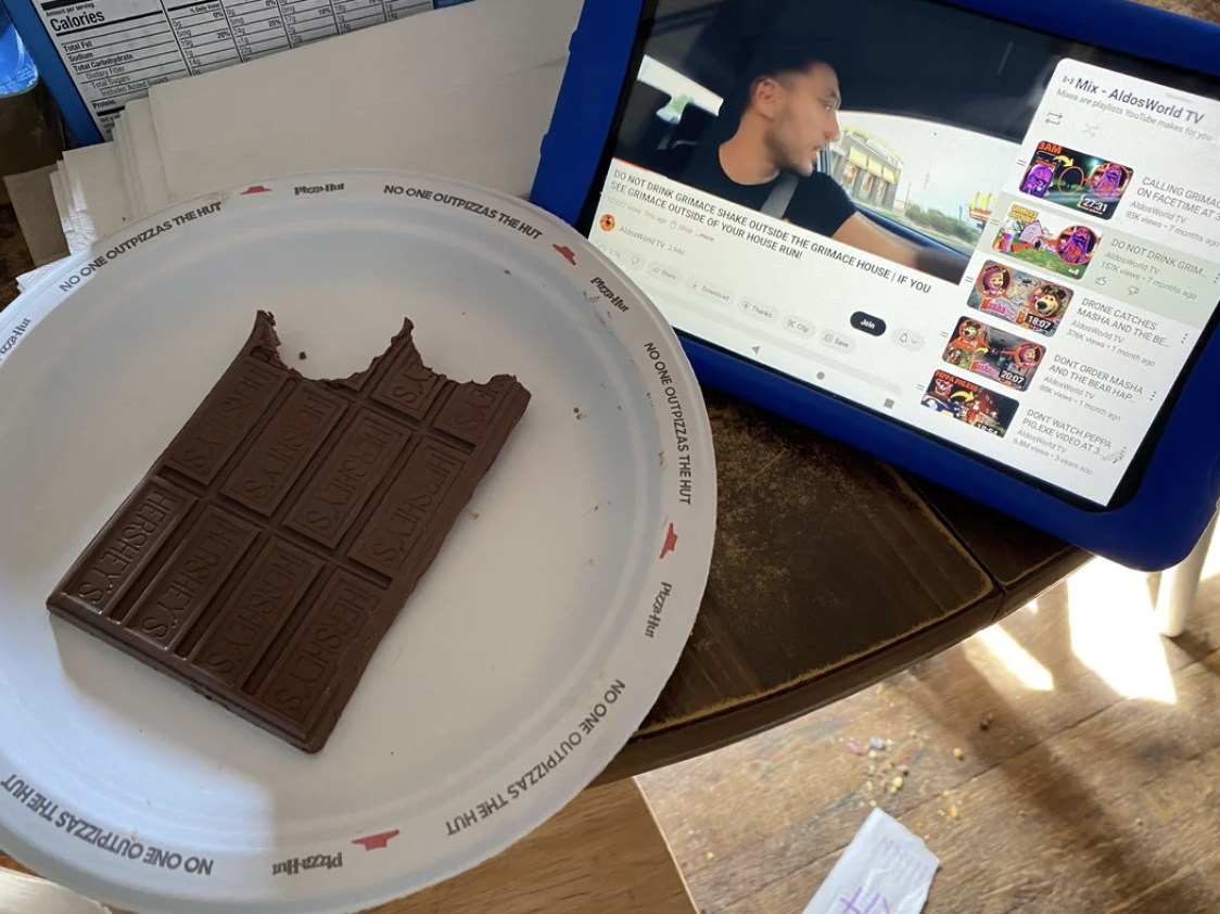 Half-eaten chocolate bar on a plate beside a tablet showing a YouTube video