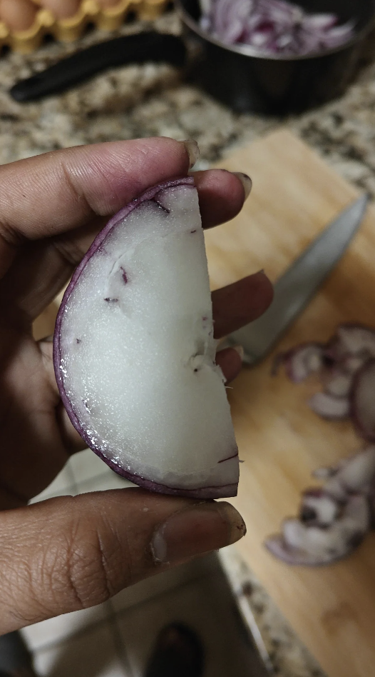 Person holding a half-sliced onion with no rings inside