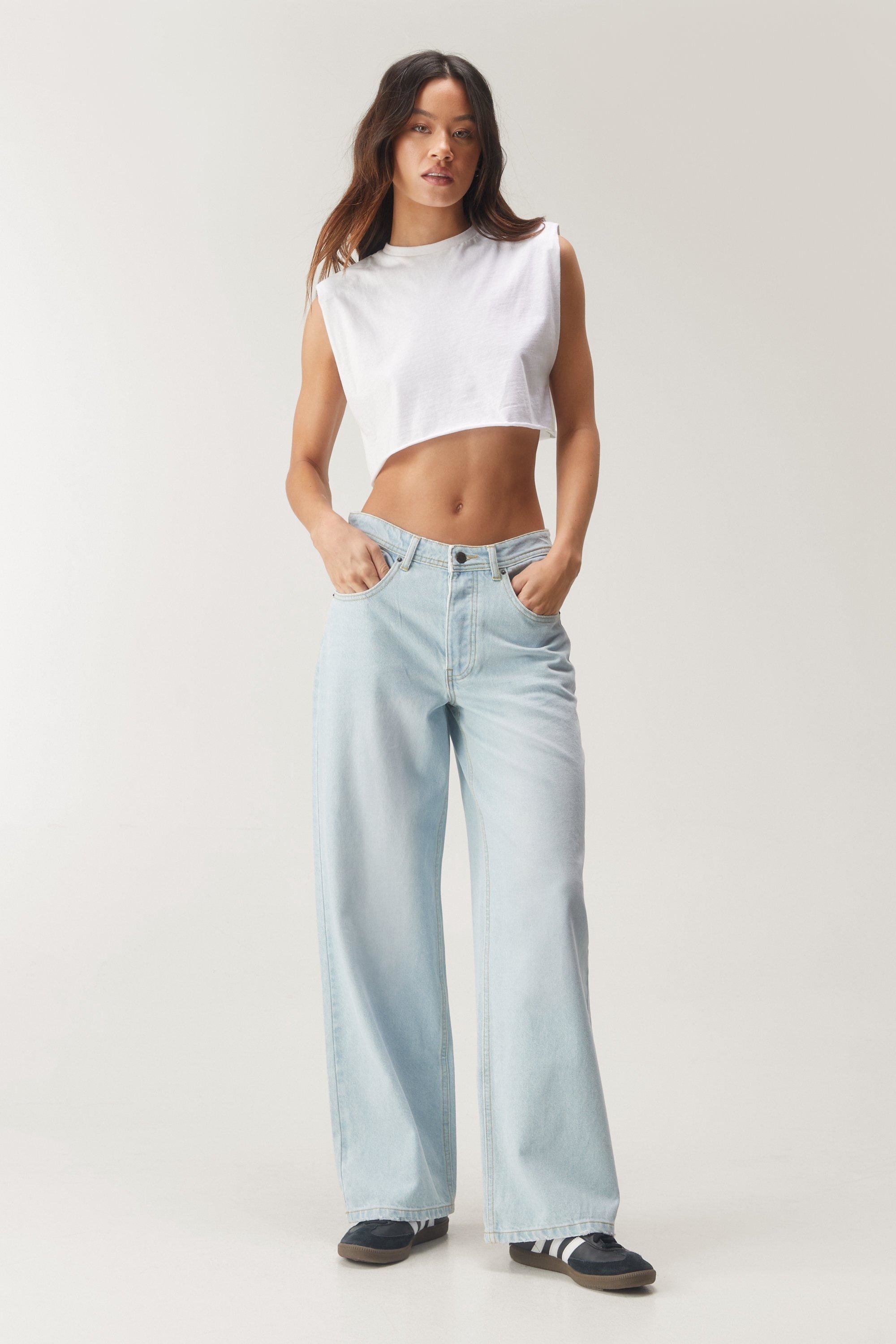 Model wearing a cropped white top and wide-leg blue jeans