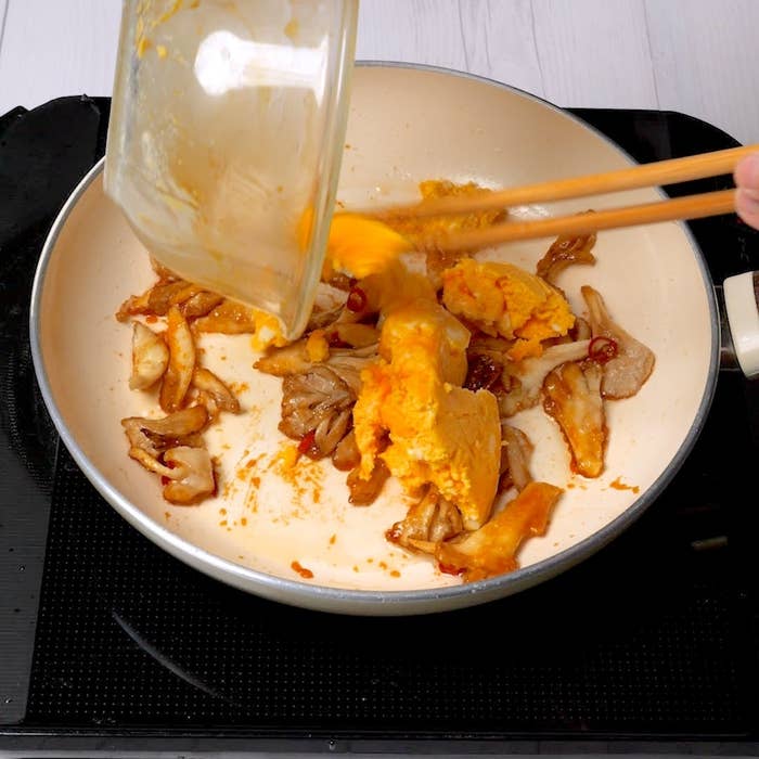 フライパンでまいたけと加熱した卵を炒める。