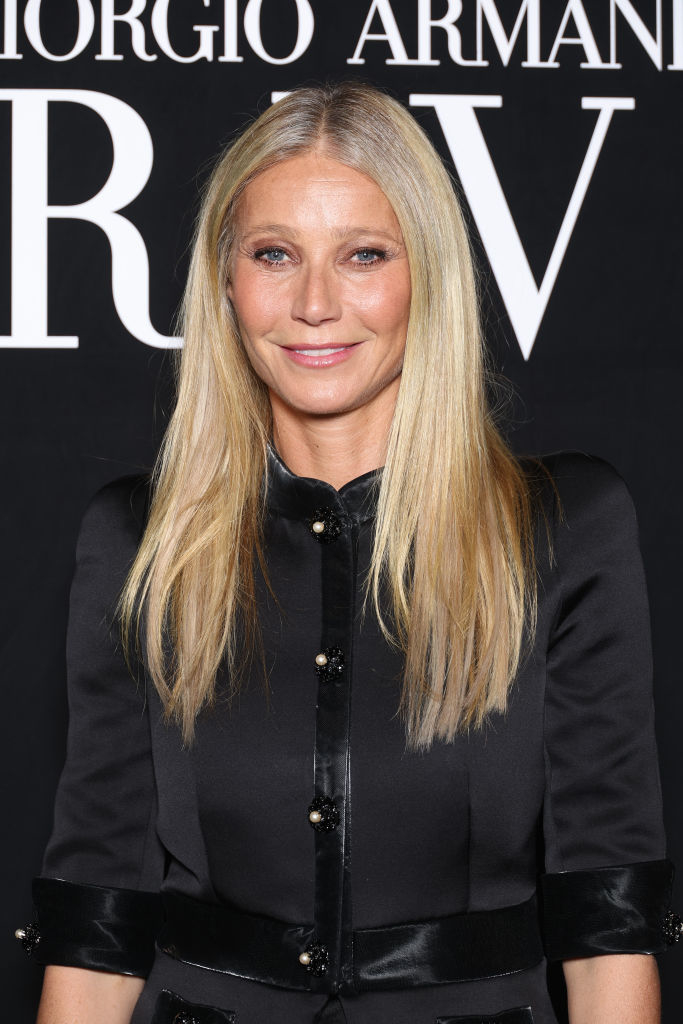 Gwyneth Paltrow posing, wearing a black buttoned outfit at a Giorgio Armani event