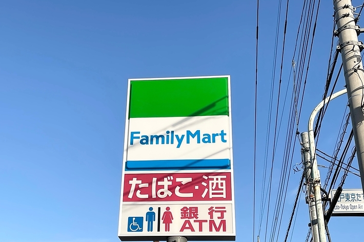 ファミリーマートの看板が青空に映える。トイレ、たばこ、駐車場、ATMの利用可能サービスが表示。