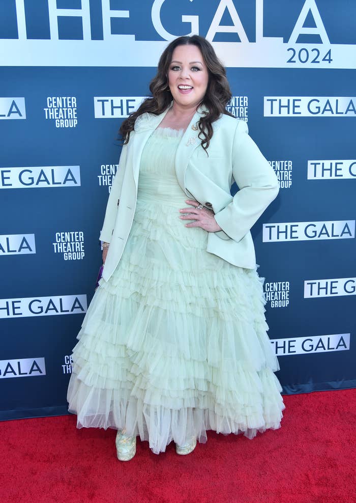Woman in a layered tulle gown and blazer posing at an event