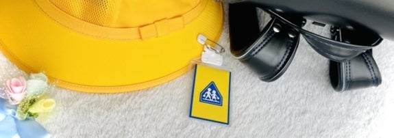 黄色のキャップと青いバッグ。バッグにはアクセシビリティマークが付いたキーホルダーがあります。