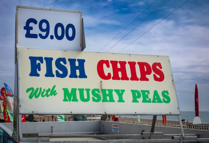 Sign advertising &quot;Fish &amp;amp; Chips with Mushy Peas&quot; for £9.00, set against a sky backdrop