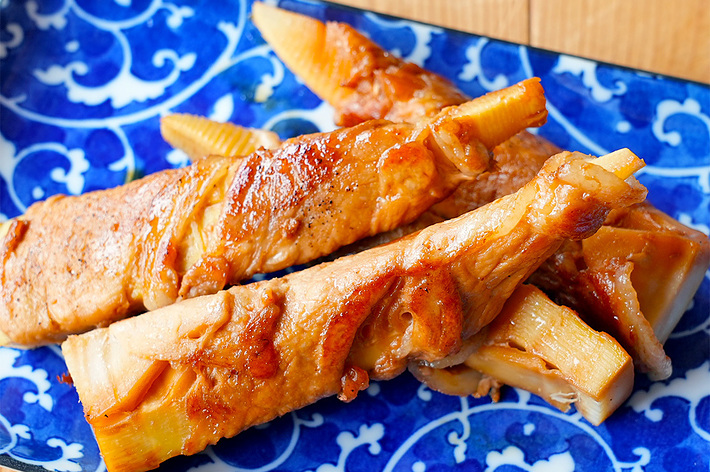 青い皿に盛られた茶色の焼きトウモロコシが3本。